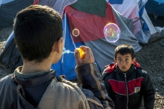 Iker Pastor, marzo 2016.  Due bambini giocano con le bolle di sapone sulla strada di un campo profughi a Idomeni, Grecia